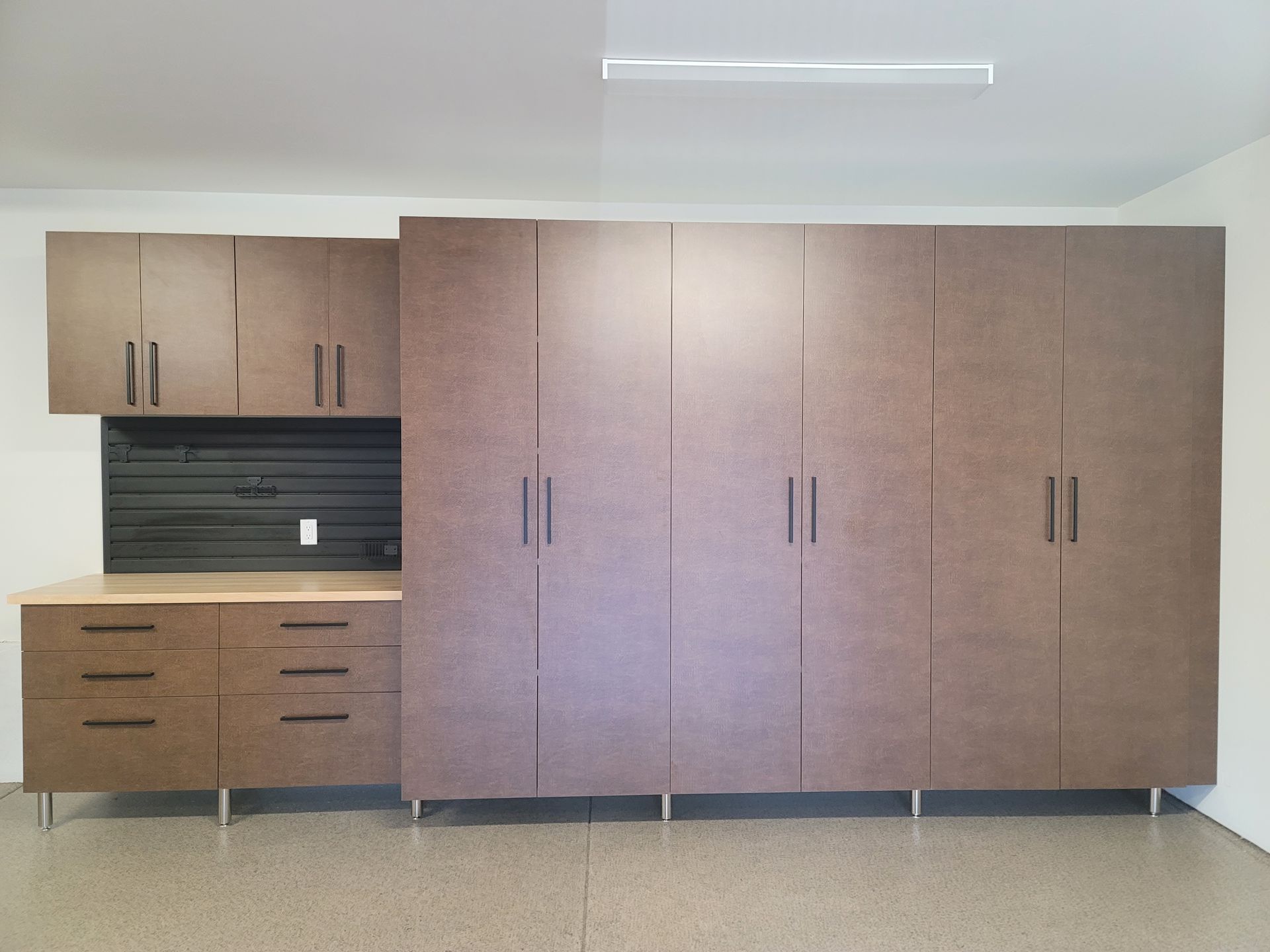 Built-in wooden cabinets and wardrobe units along a wall in a minimalist room