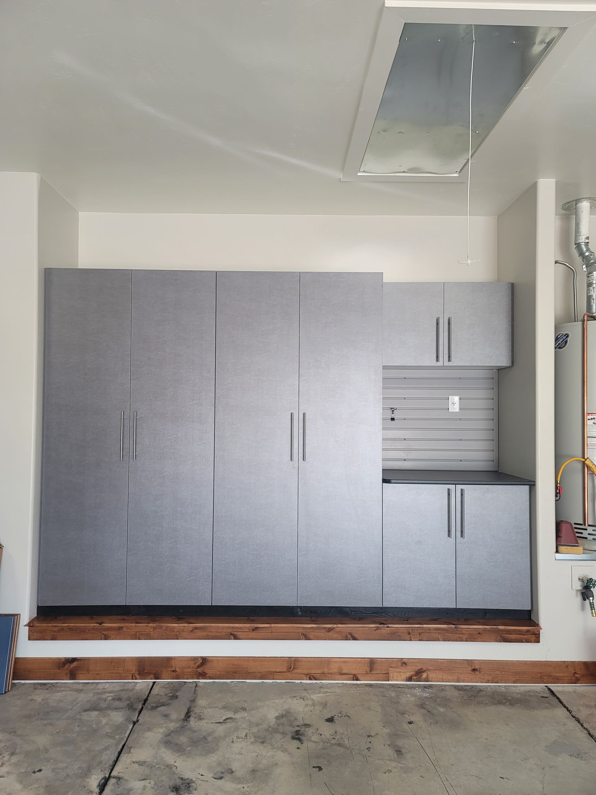 Gray storage cabinets in a garage, with a concrete floor and overhead fluorescent light.