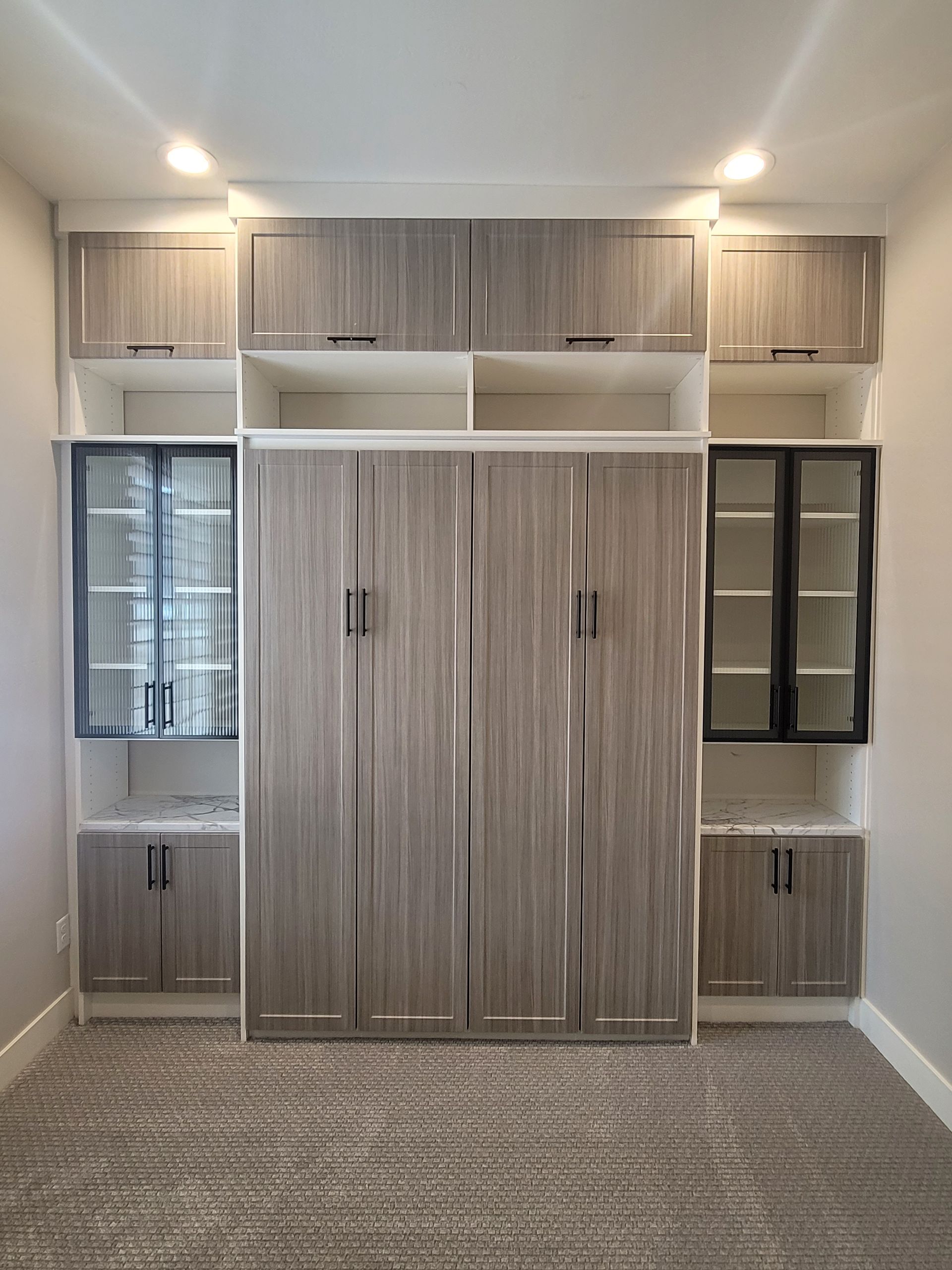 Empty walk-in closet with white shelves, drawers, and a small bench in the center.