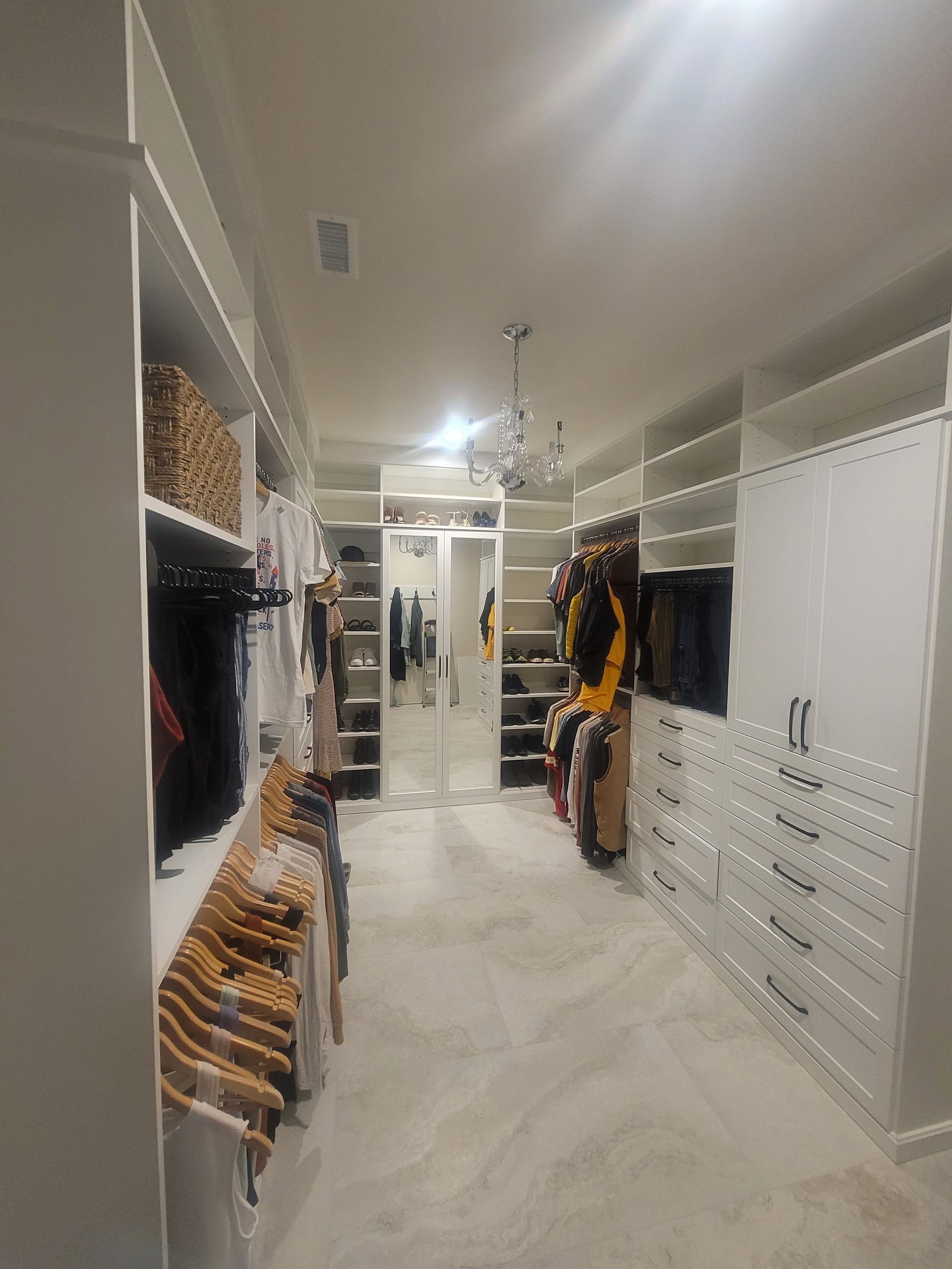 Walk-in closet with built-in shelves, white cabinetry, and a wood floor under recessed lighting.