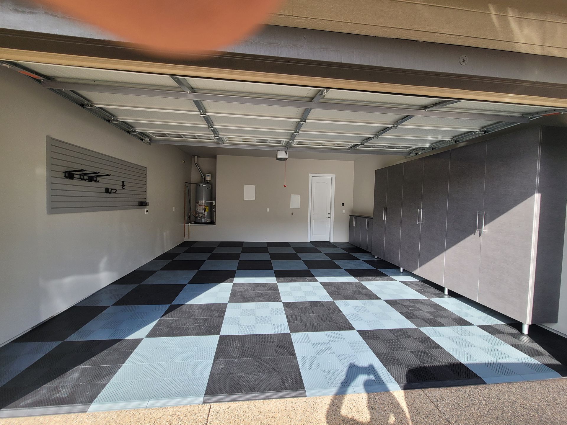 Empty garage with checkered floor, gray walls, and a closed white door.