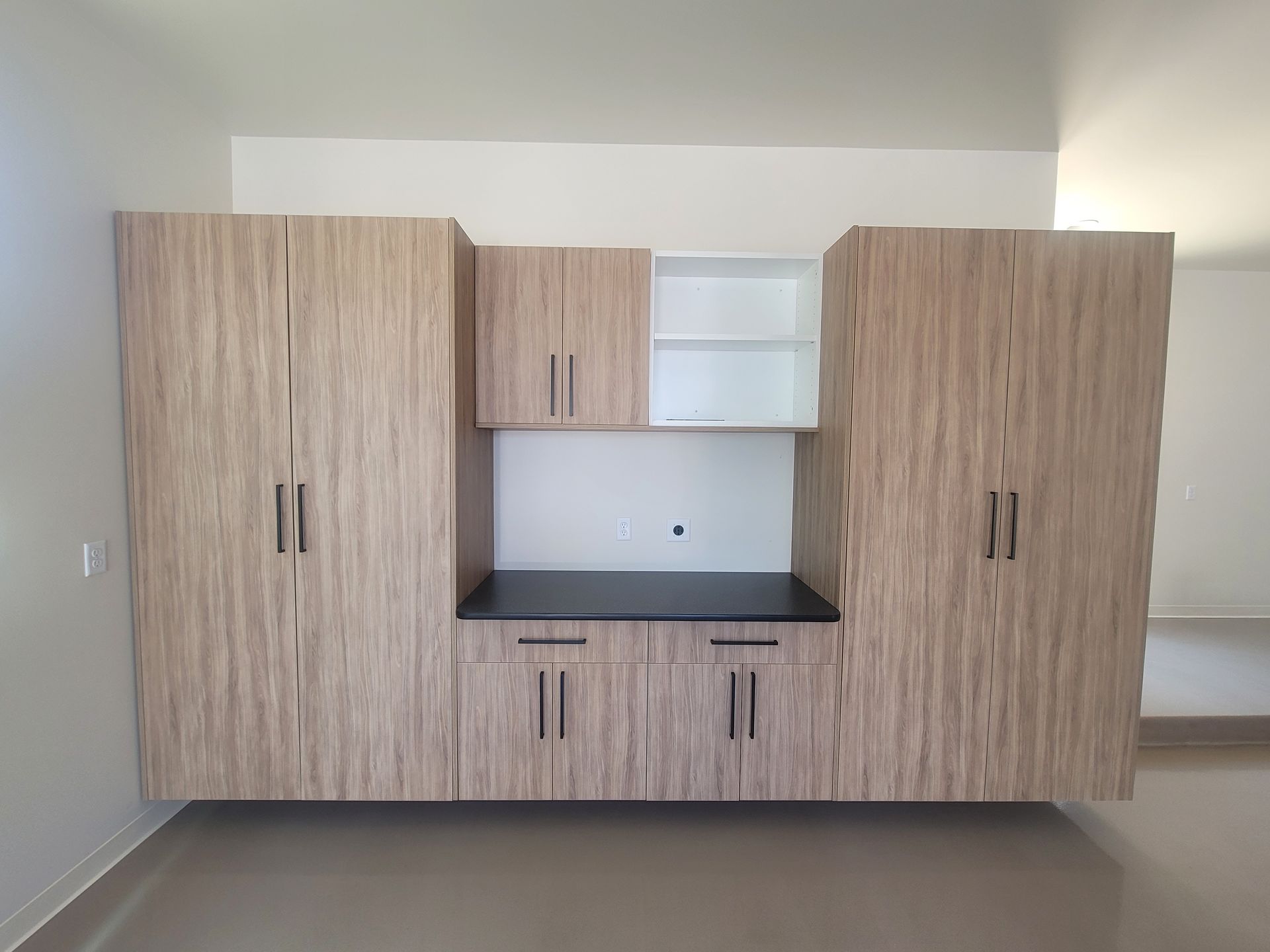 Built-in wood cabinetry with dark countertop in an empty room