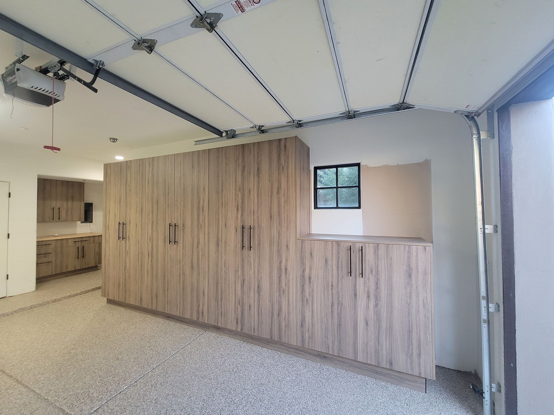 Empty modern garage with wood-paneled storage cabinets and a gray speckled floor