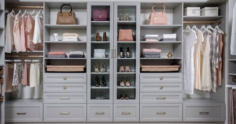 Walk-in closet with white shelving, drawers, hanging clothes, handbags, shoes, and folded linens