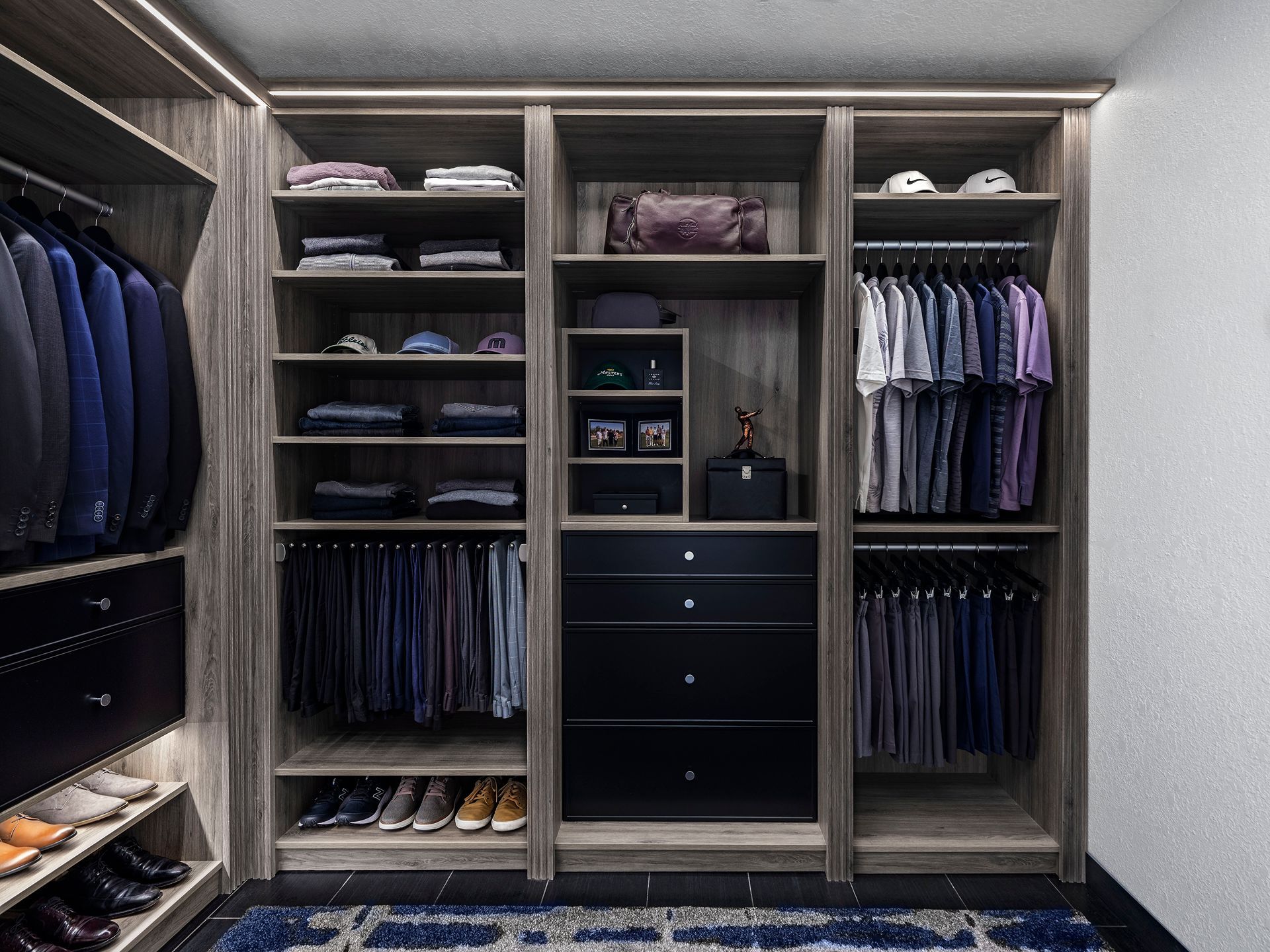 A well-organized walk-in closet with teal cabinetry and white shelving. Clothes hang, and decorative items are on display.