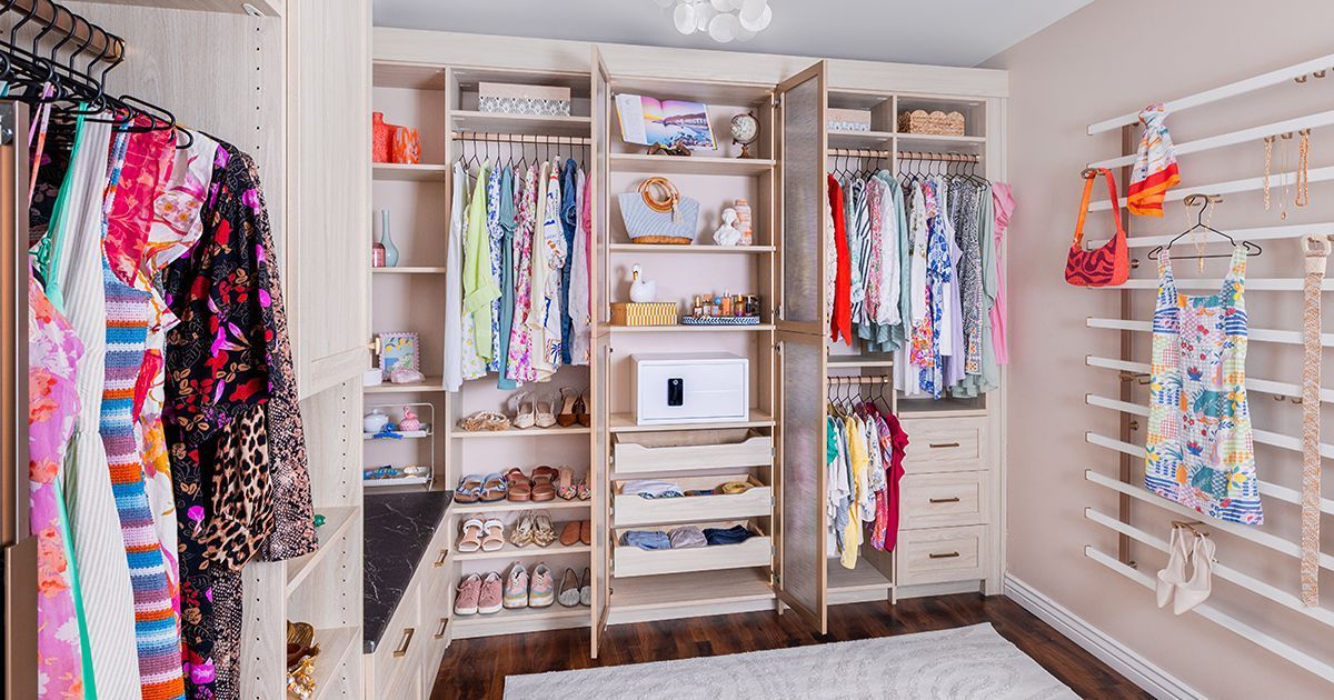 Walk-in closet with organized clothes and shoes, light wood cabinets, and a white rug.