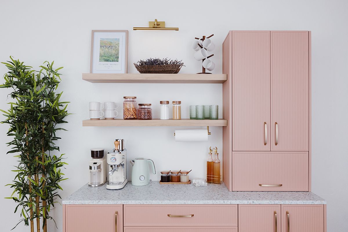 Pink kitchen with open shelves, potted plant, and countertop appliances