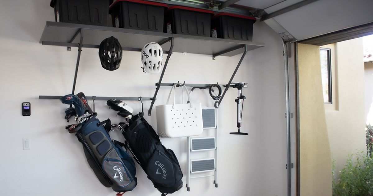 Garage wall with hanging golf bags, helmets, and shelves near an open doorway