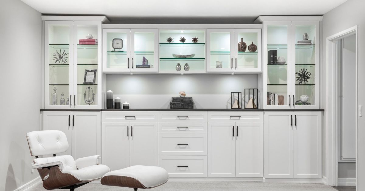 Bright white living room with built-in cabinets, glass shelves, and a lounge chair by the wall
