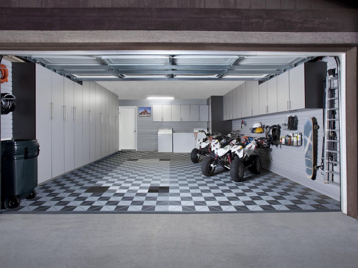 Open garage with checkered floor, white cabinets, and two motorcycles inside.
