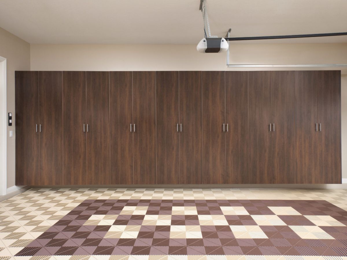 Garage with a long brown storage wall, ceiling-mounted opener, and checkered floor mats