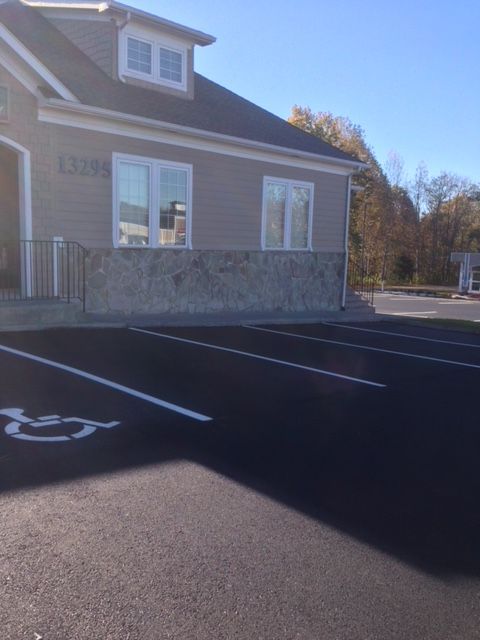 Exterior of a building with parking; a handicap parking space is marked with white paint.