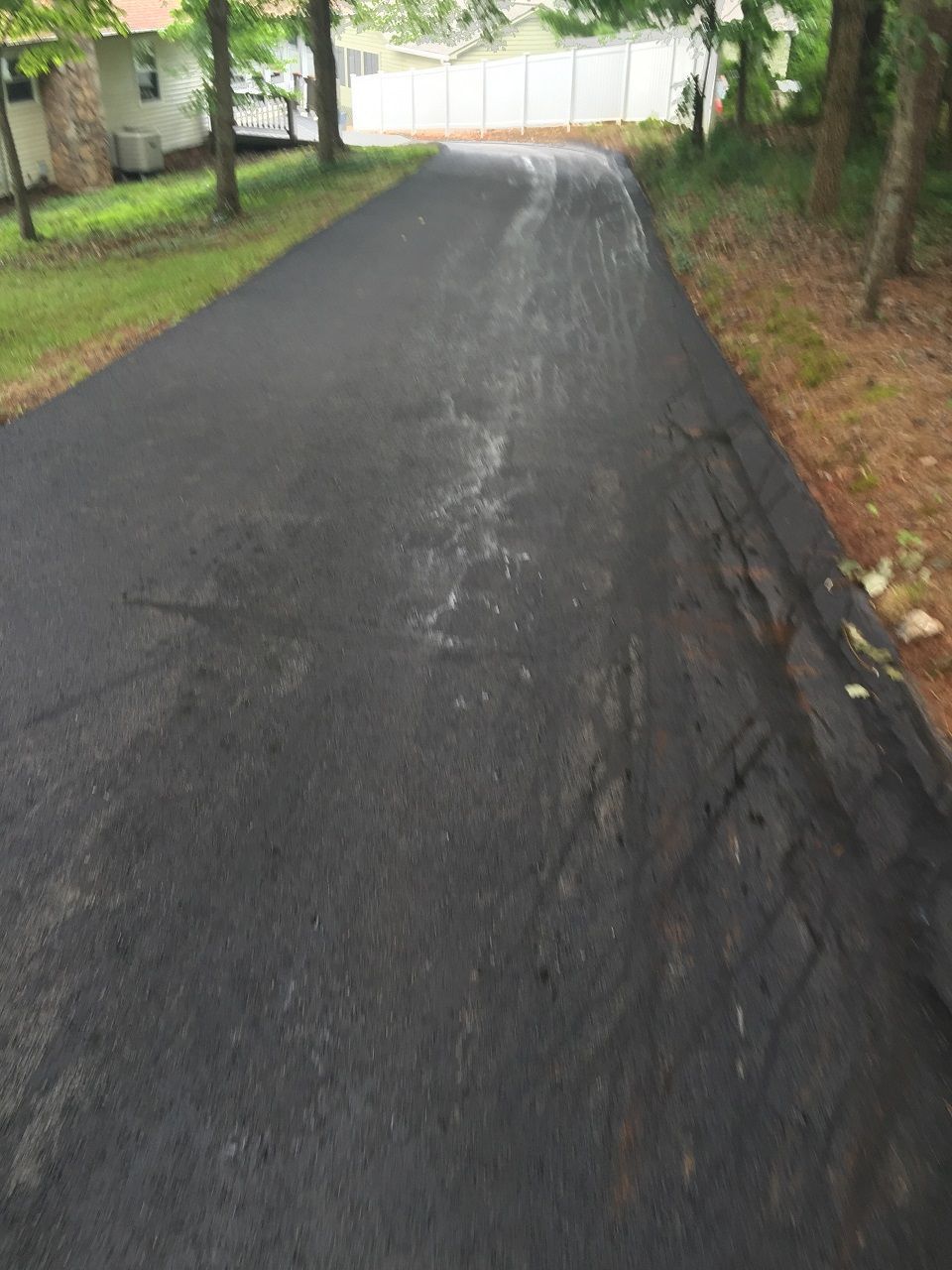 Newly paved black asphalt driveway curves upwards.
