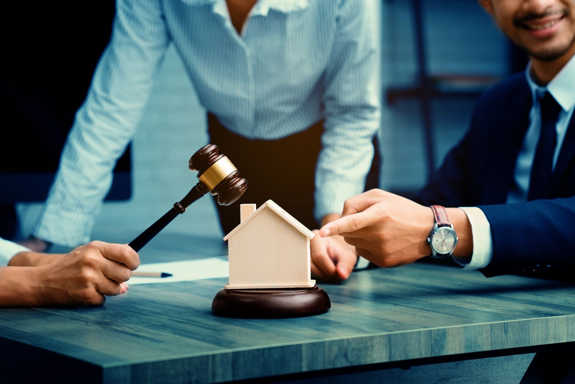 Businesspeople with gavel and house model at a desk during a real estate auction