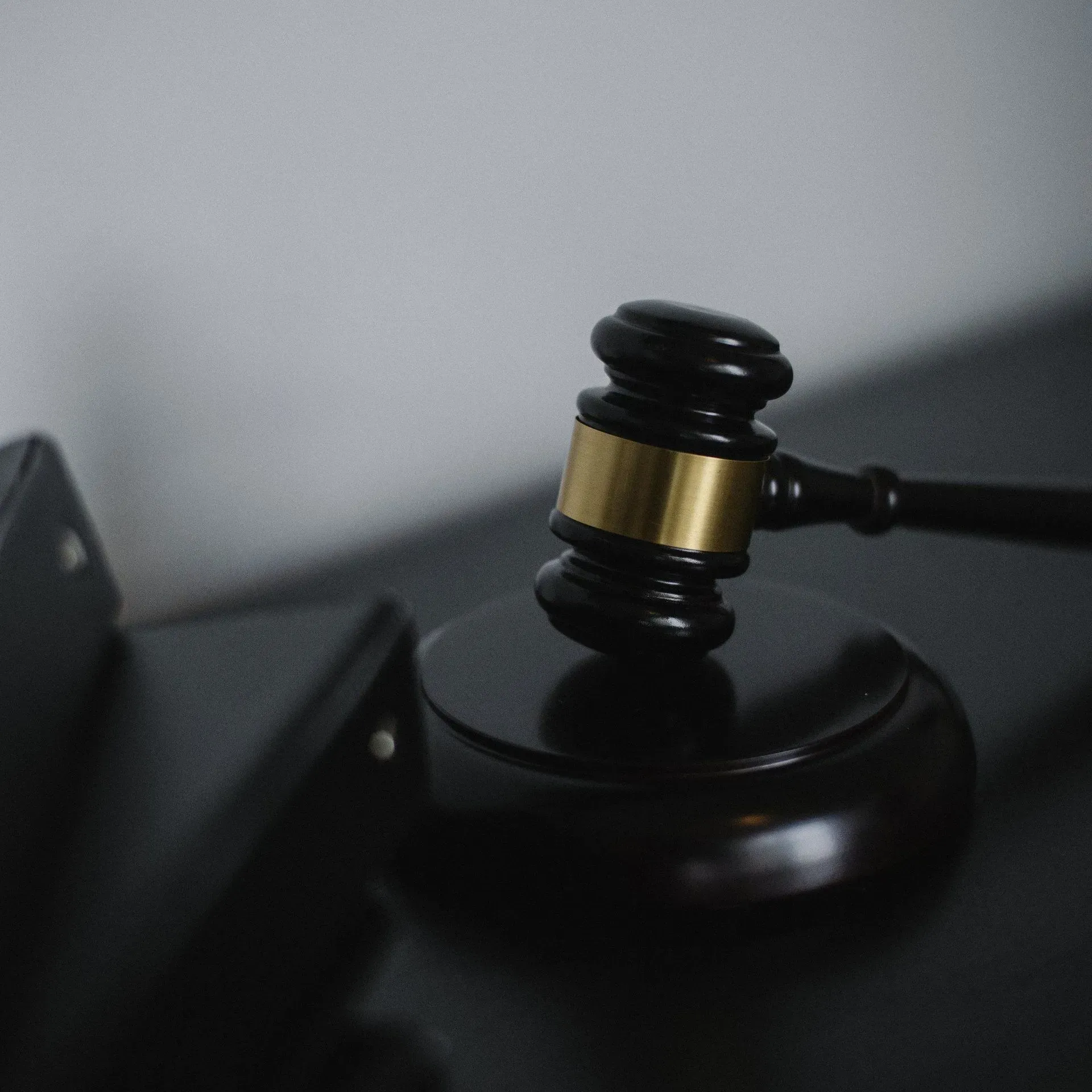 Black gavel with gold band resting on a desk beside a closed laptop