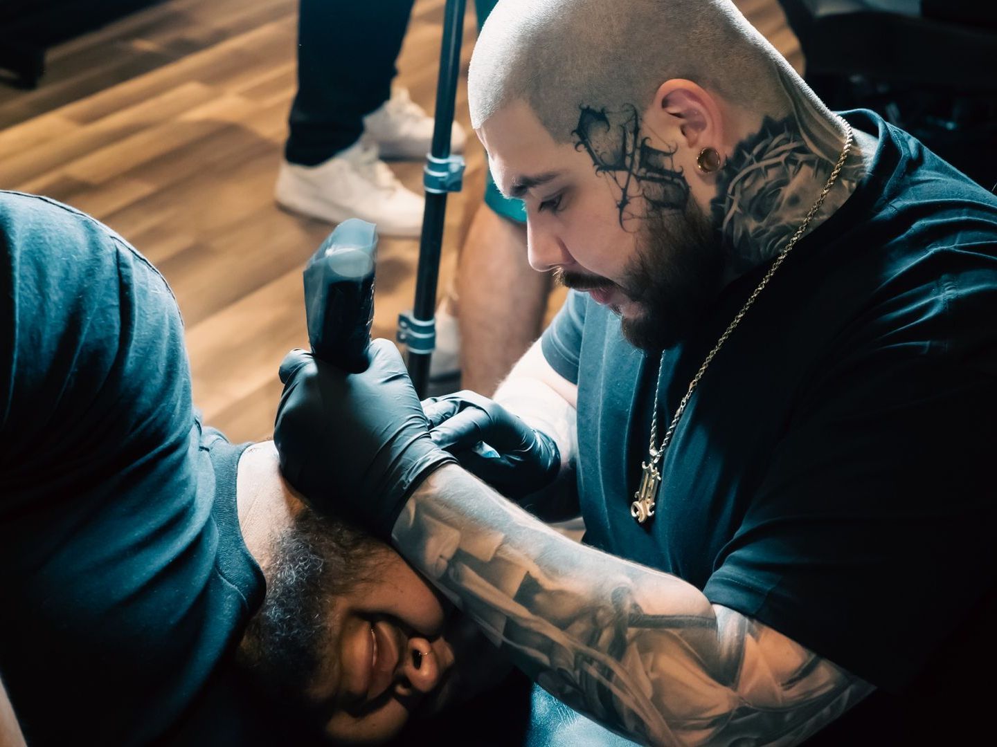 Gueroe tattooing with a tattoo light that looks like a halo behind his head