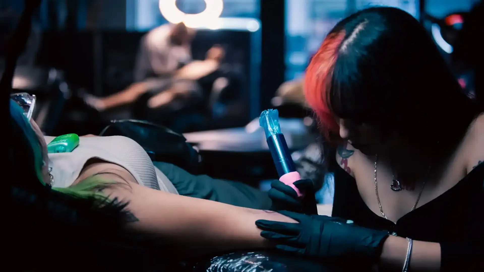 A female tattoo artist working on a client's wrist