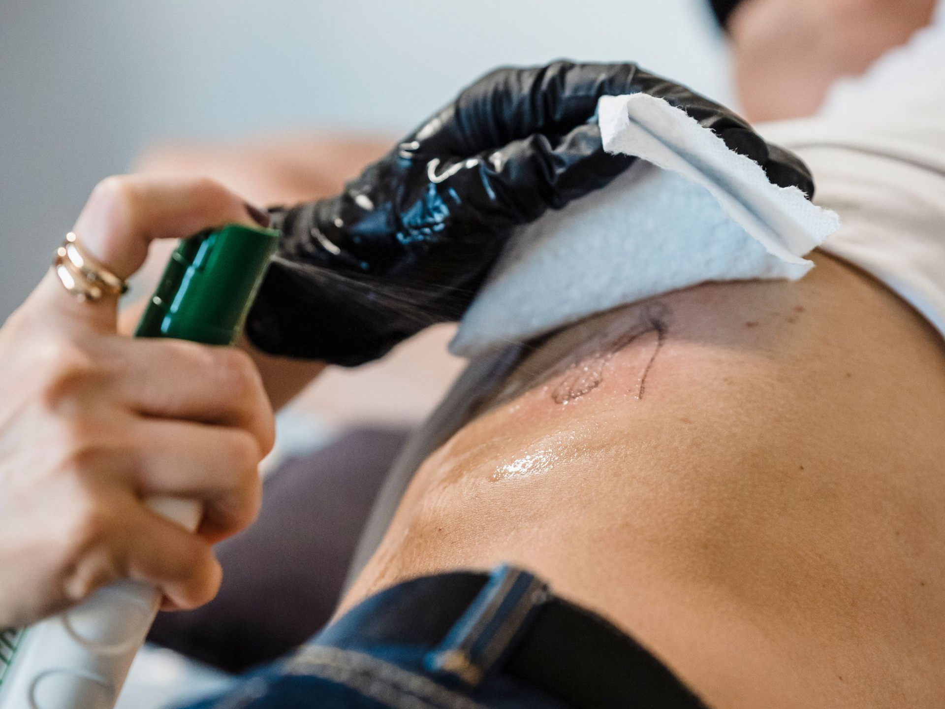 Tattoo artist cleaning a freshly tattooed area with a gloved hand
