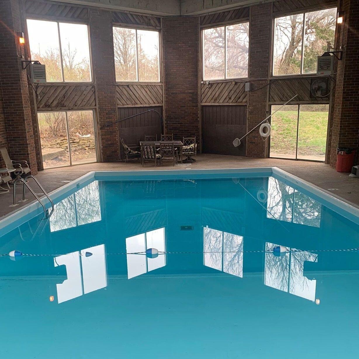 Indoor swimming pool reflecting windows, set in a room with brick walls and natural light.