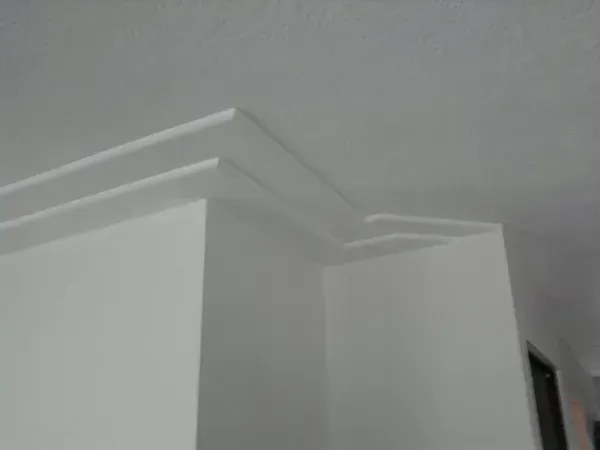 White interior ceiling and wall corner with crown molding, viewed from below