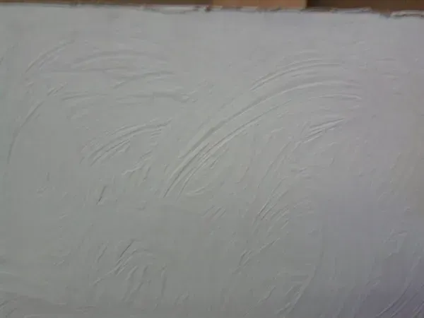 White textured wall or ceiling surface with subtle curved plaster patterns.