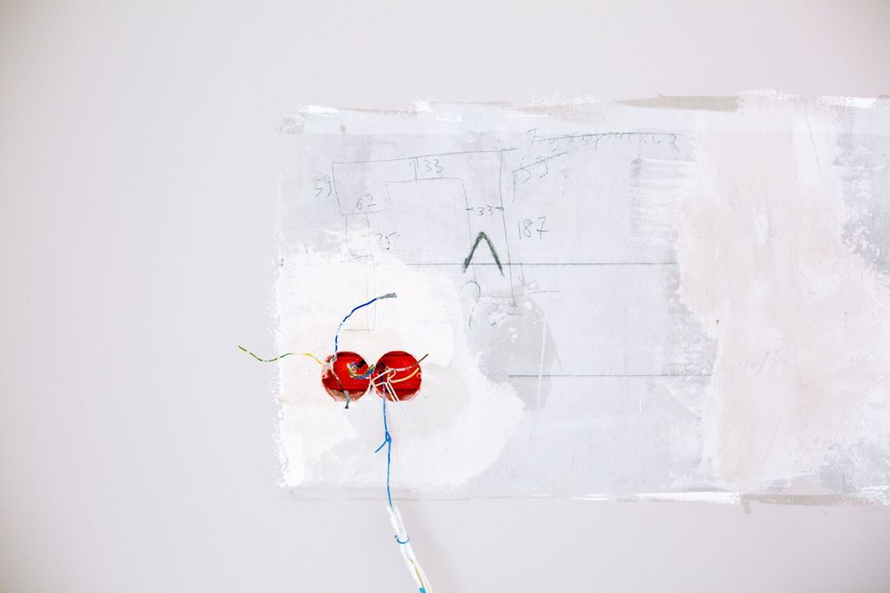 Two red round objects on a white wall with a thin blue string hanging down