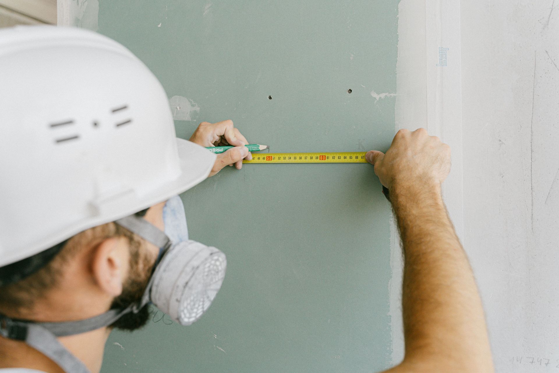 Worker measuring a wall with a tape measure during construction work