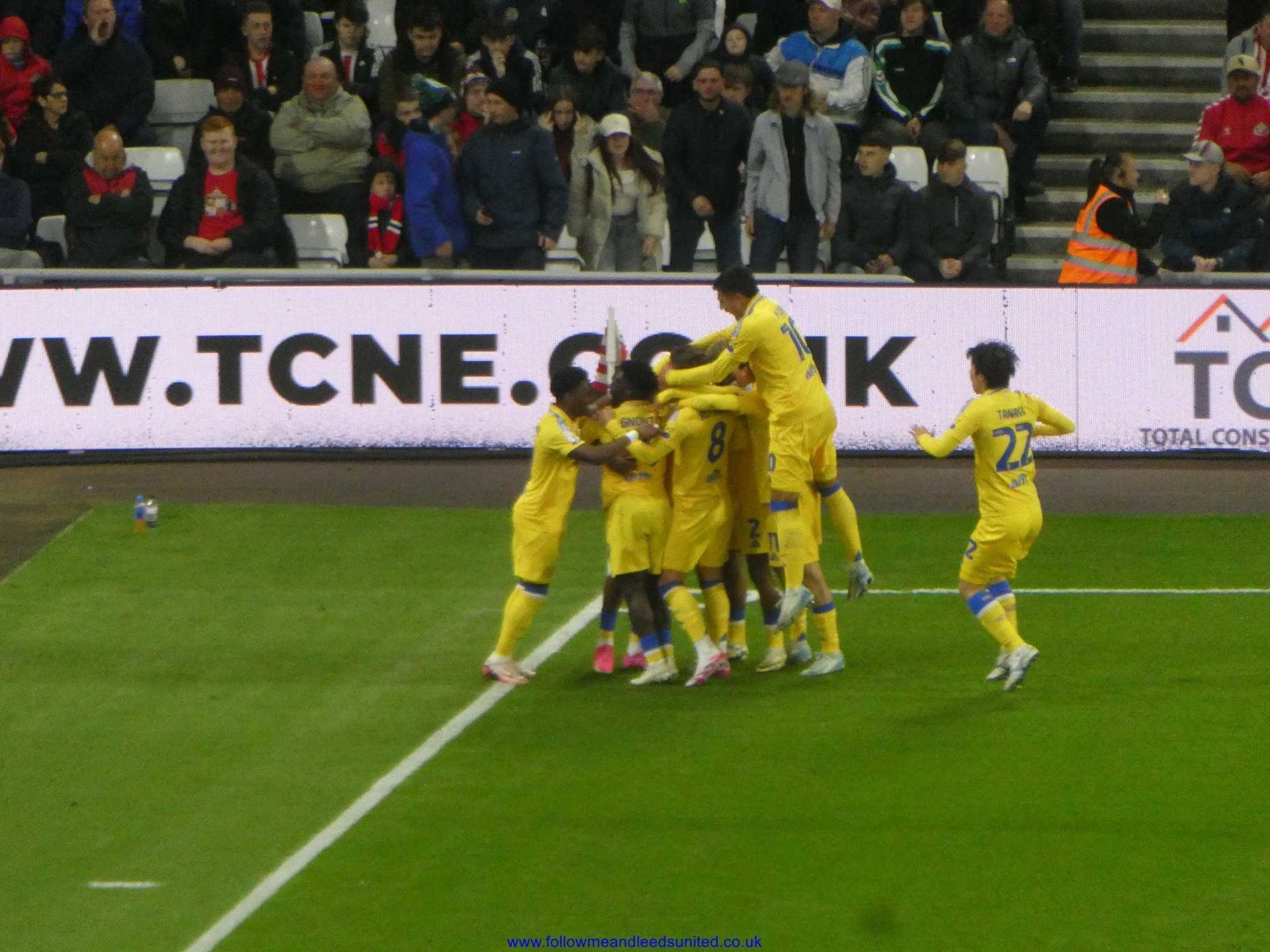 A group of soccer players on a field with a banner behind them that says vw.tcne.co.uk