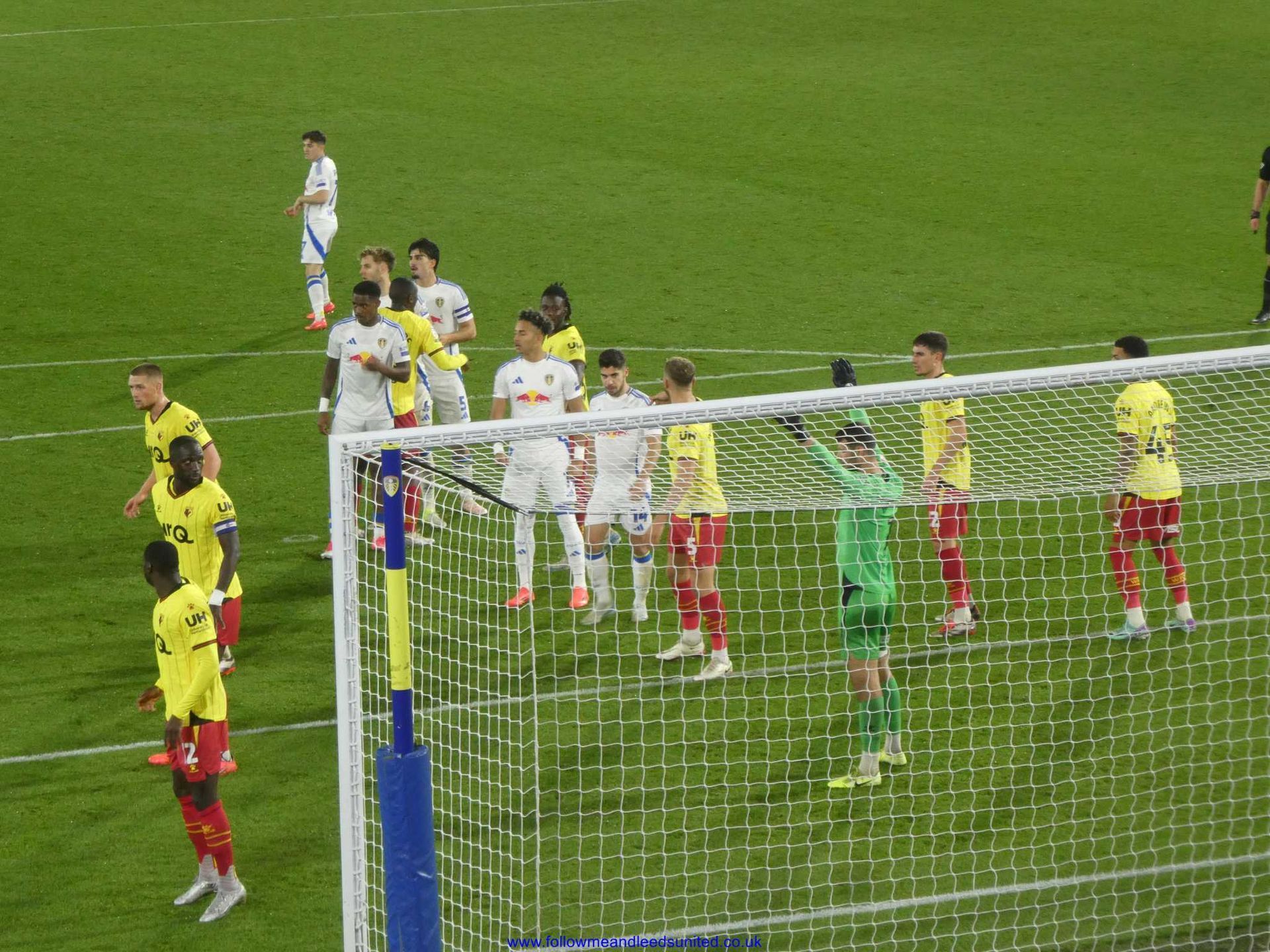 A group of Leeds United and Watford players are standing on a pitch in front of a goal during their game on 22nd October 2024 at Elland Road