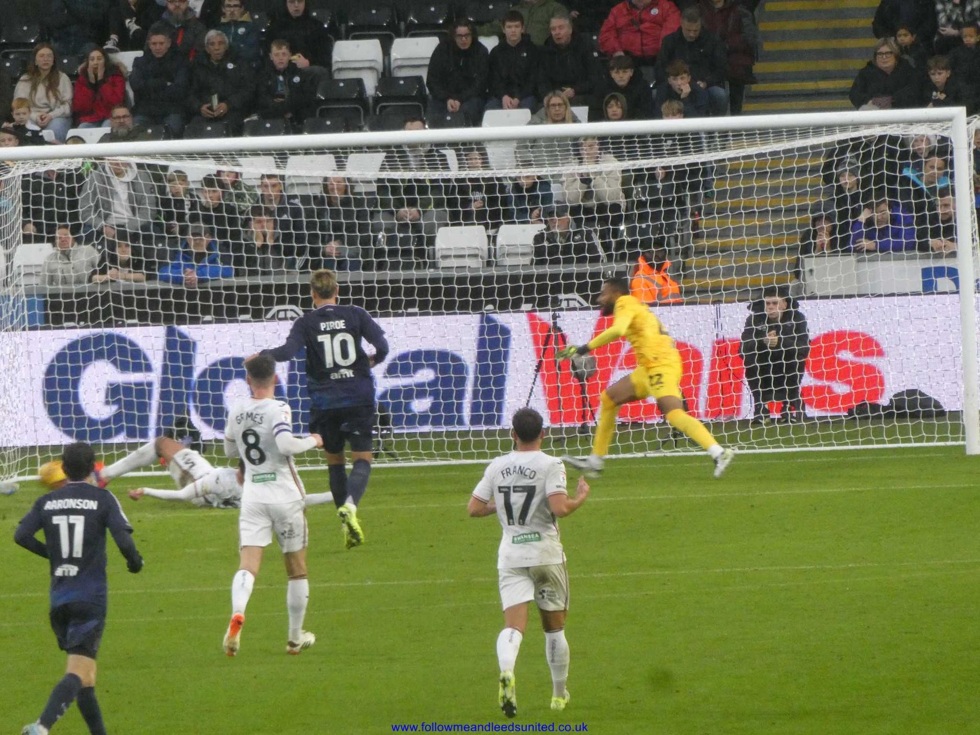 A soccer game is being played in front of a sign that says global walls