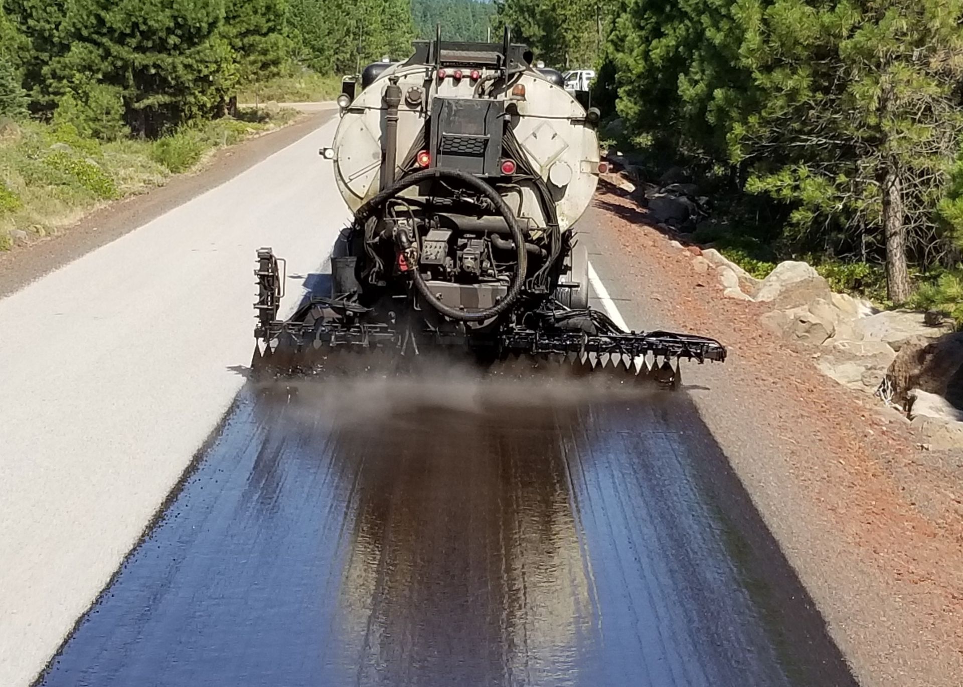 A truck is spraying asphalt on a road