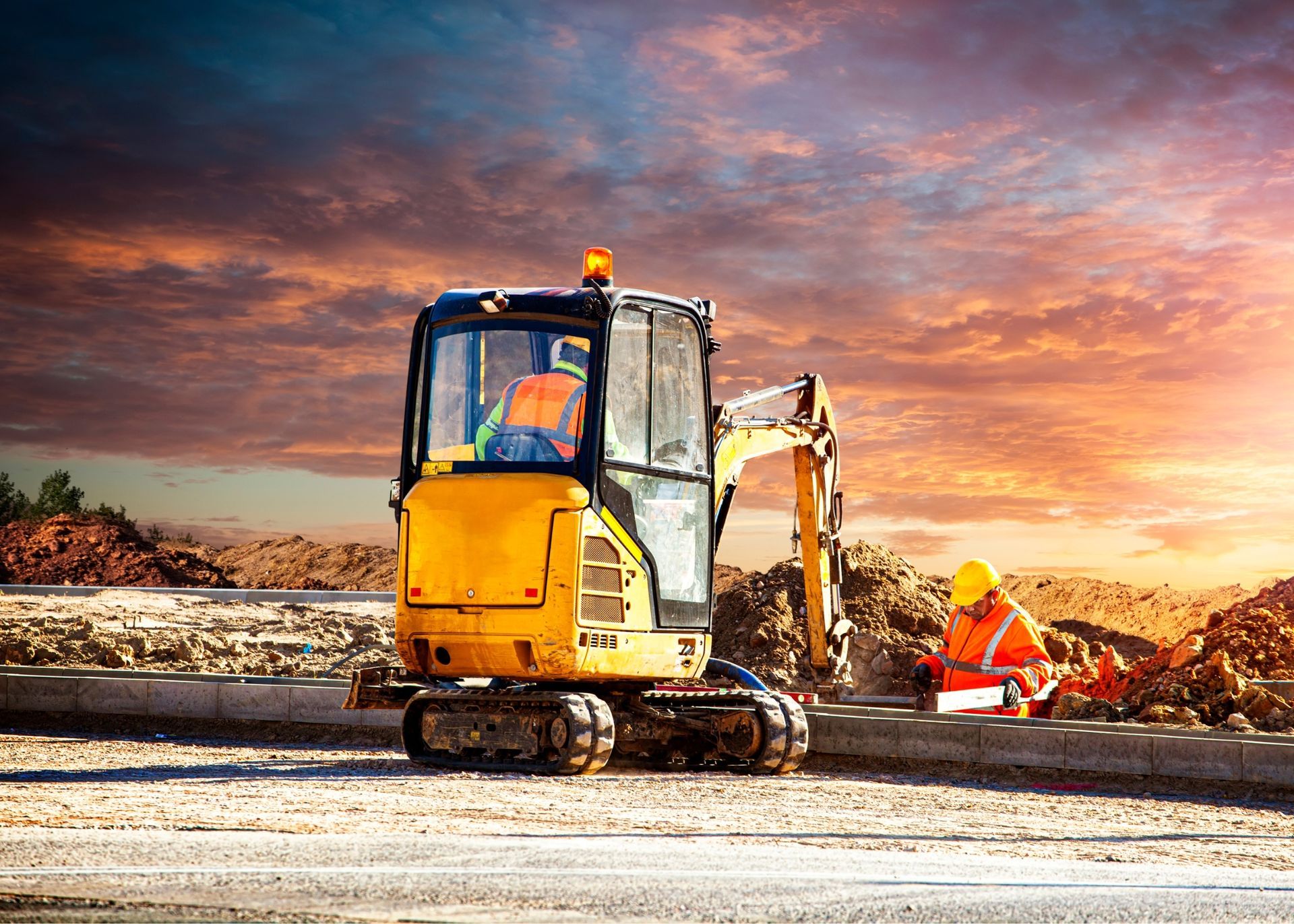 A bulldozer/excavator is parked on a construction site at sunset.