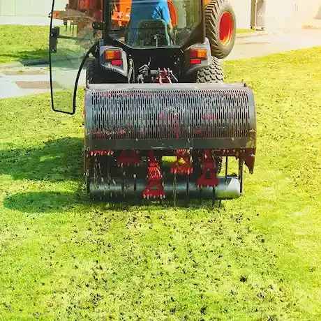 A tractor is spreading fertilizer on a lush green lawn.