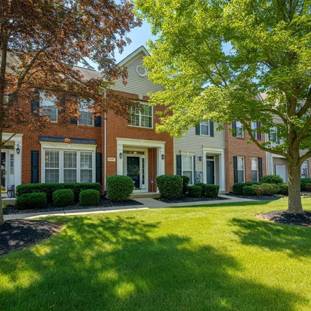A brick house with a lush green lawn in front of it