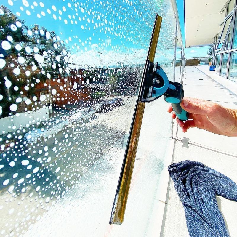 Worker squeegeeing a large house window