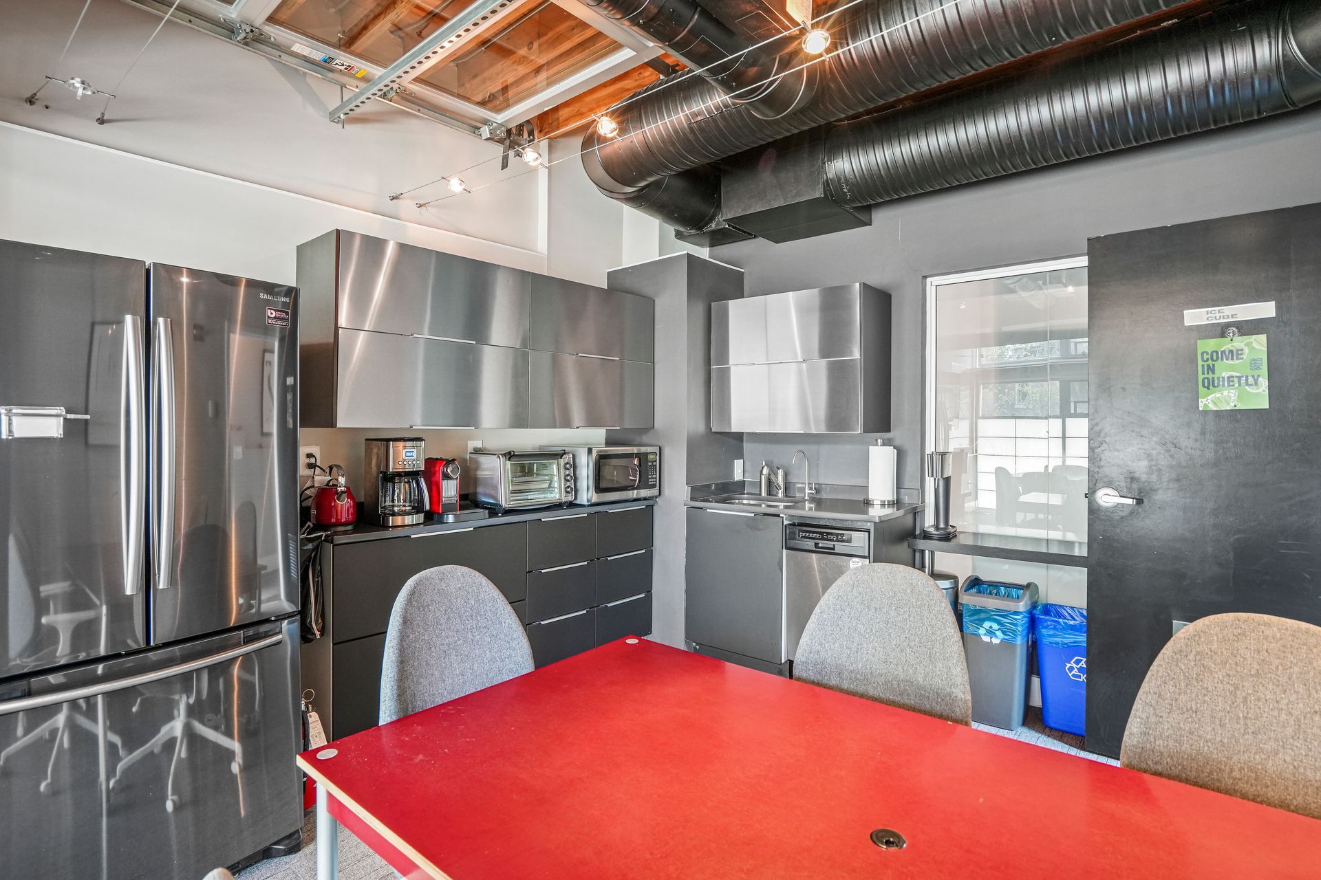 Open office workspace with kitchenette and exposed ceiling beams
