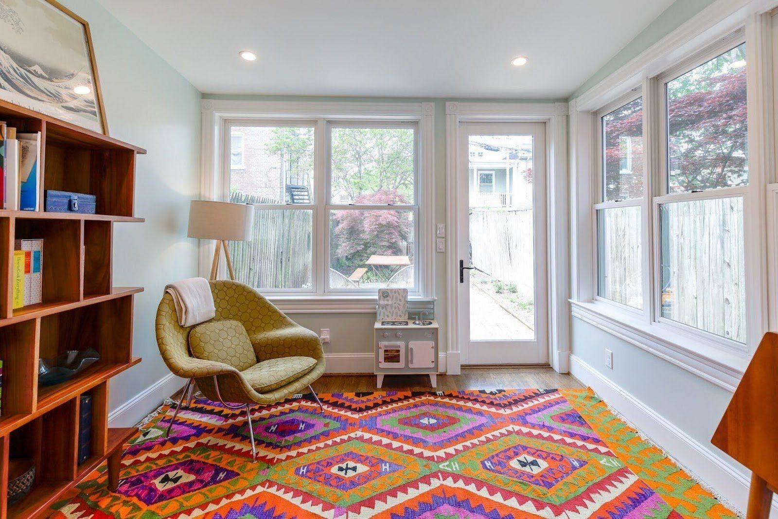 Sunroom with bookshelf comfortable chair and bright rug