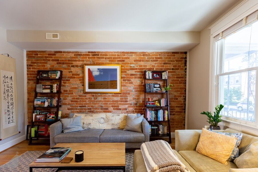 Cozy DC living room with couch and exposed brick wall, reflecting the city’s rental property and apartment rental market.