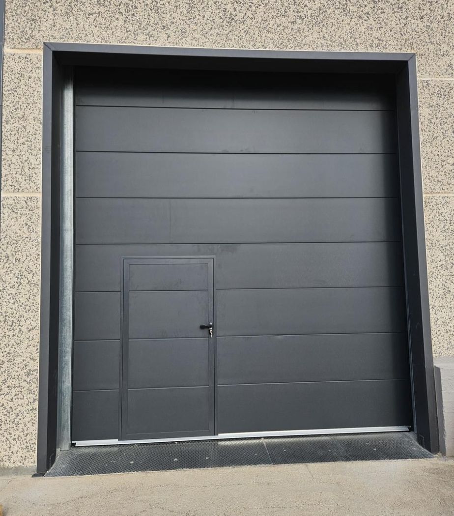 Una porta da garage grigia è parzialmente aperta, rivelando un'auto parcheggiata all'interno di un garage residenziale.