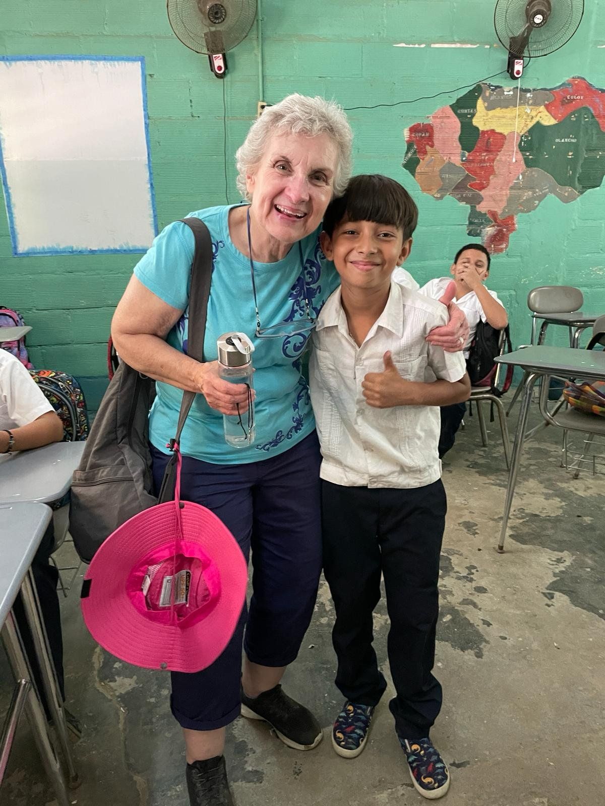 A woman is standing next to a boy in a classroom.