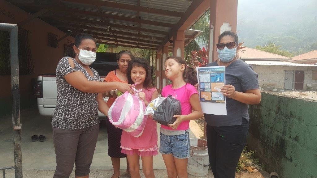 A group of people wearing face masks are standing in front of a house.