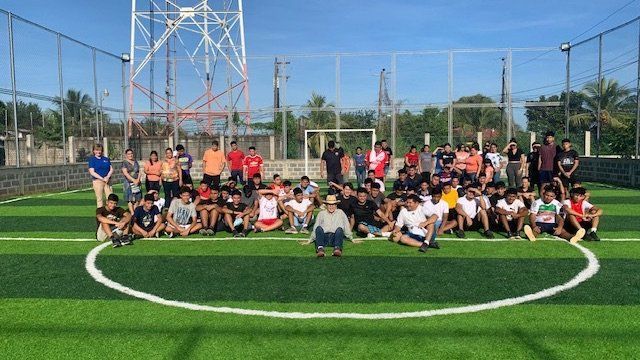 A group of people are posing for a picture on a soccer field.