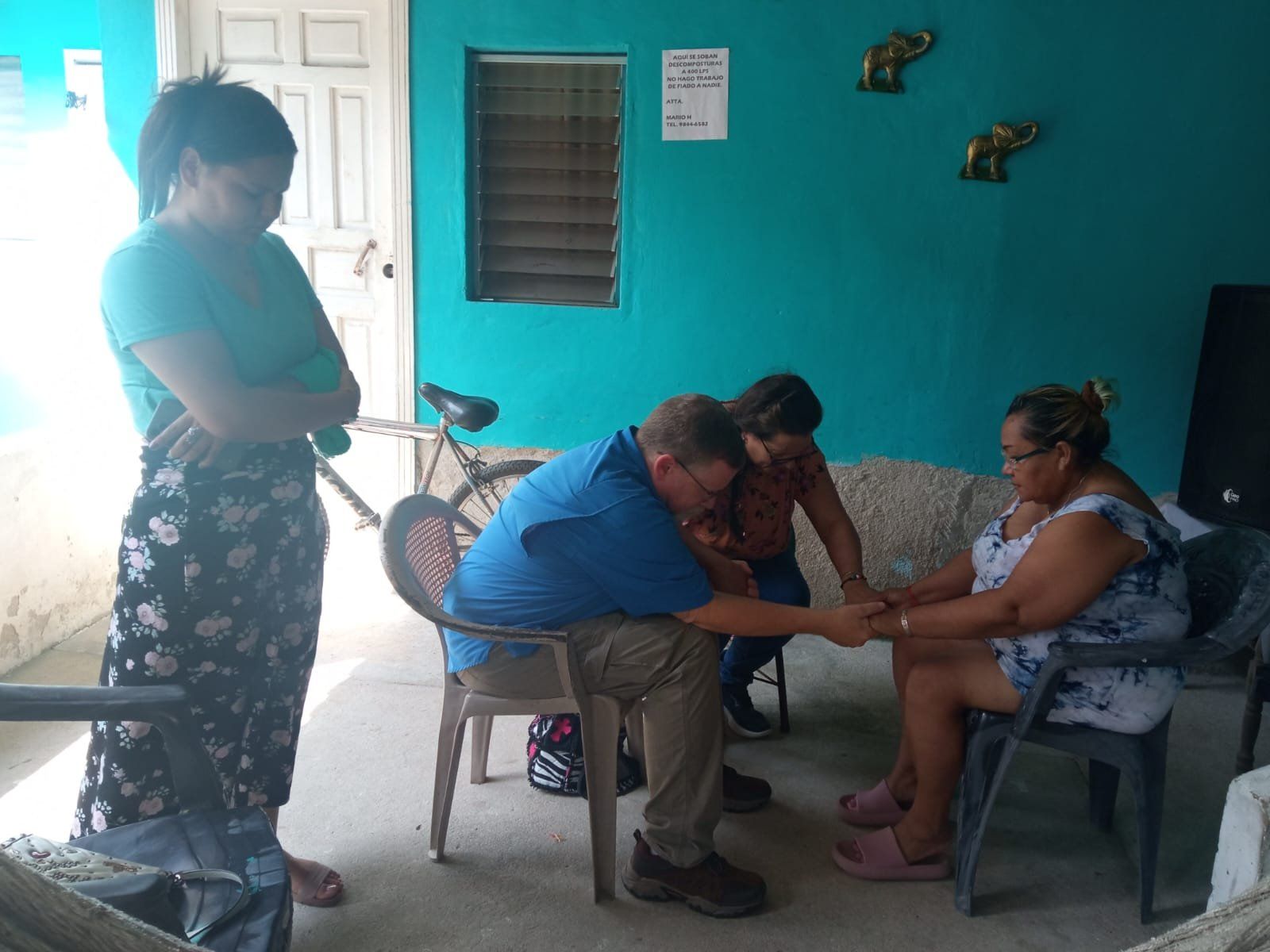 A group of people are holding hands in a room with a blue wall