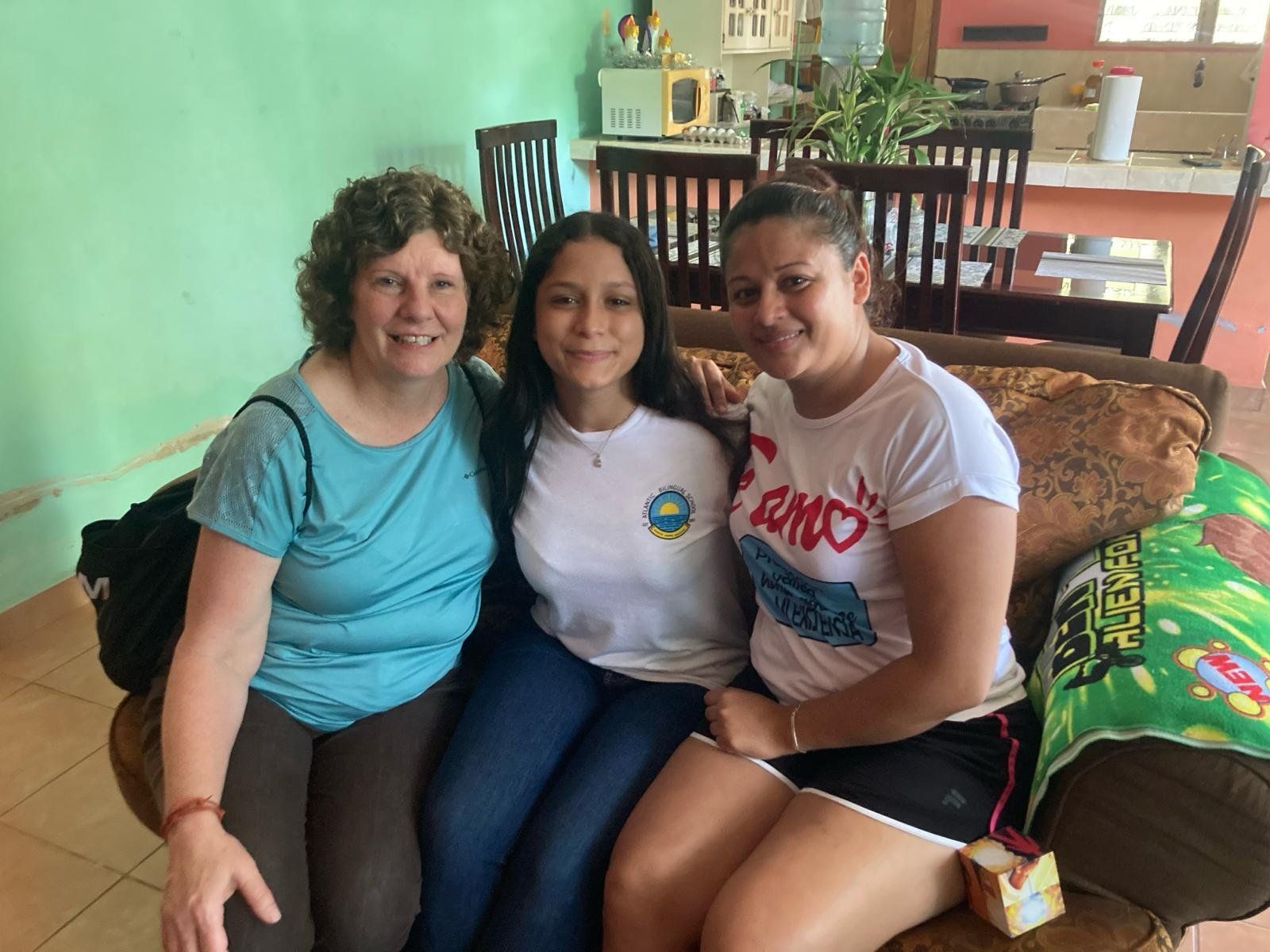 Three women are posing for a picture while sitting on a couch.