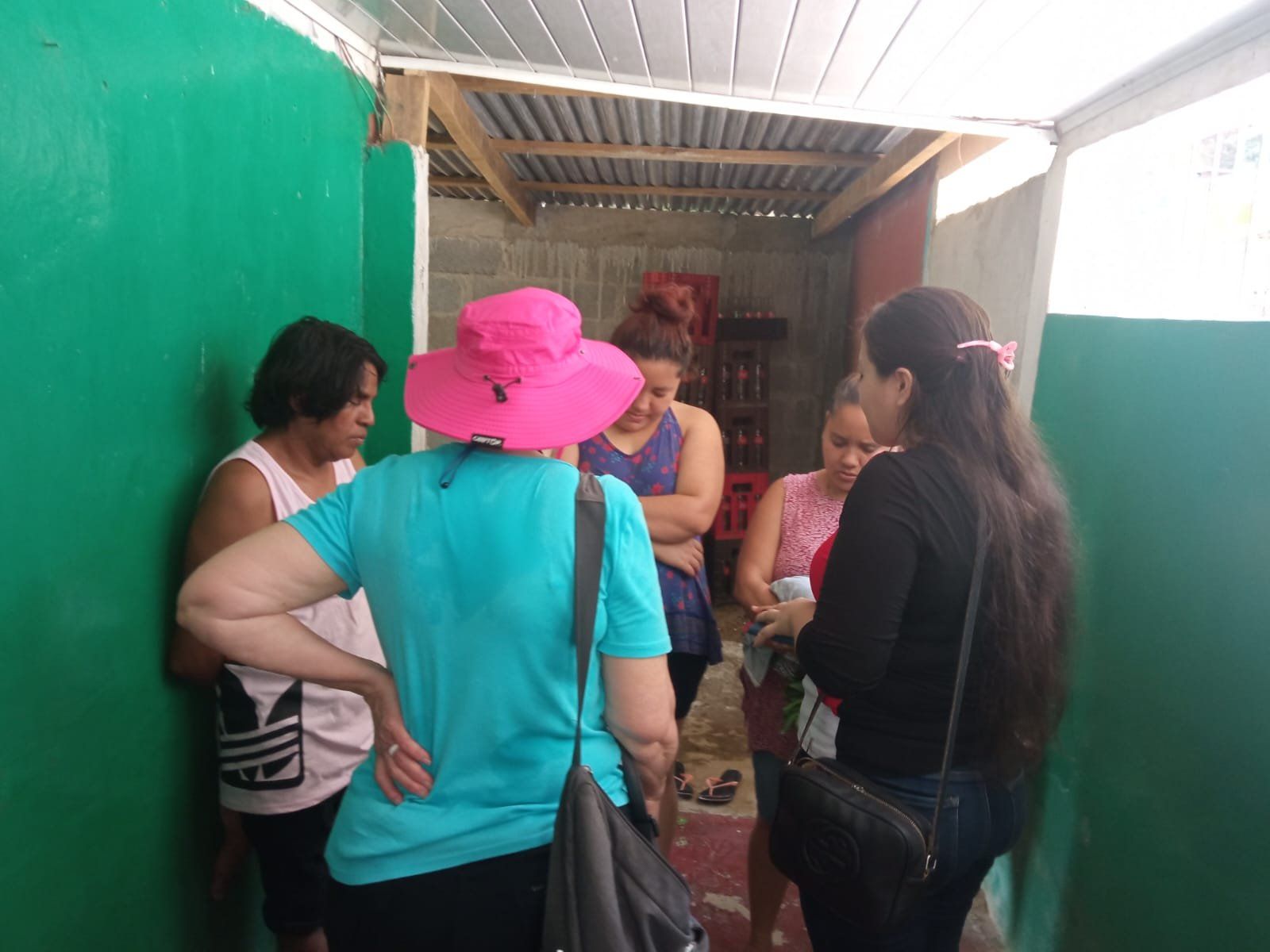 A group of women are standing in a room talking to each other.
