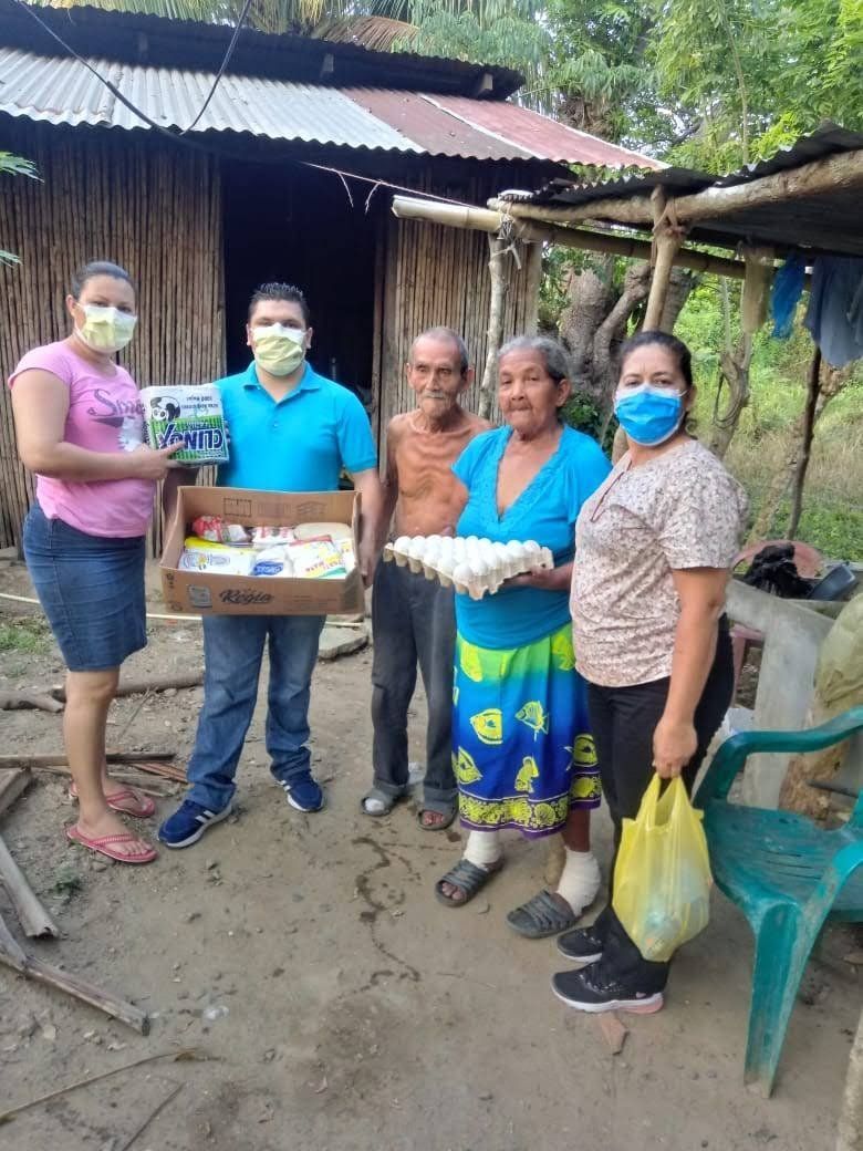 A group of people wearing face masks are standing in front of a wooden house.