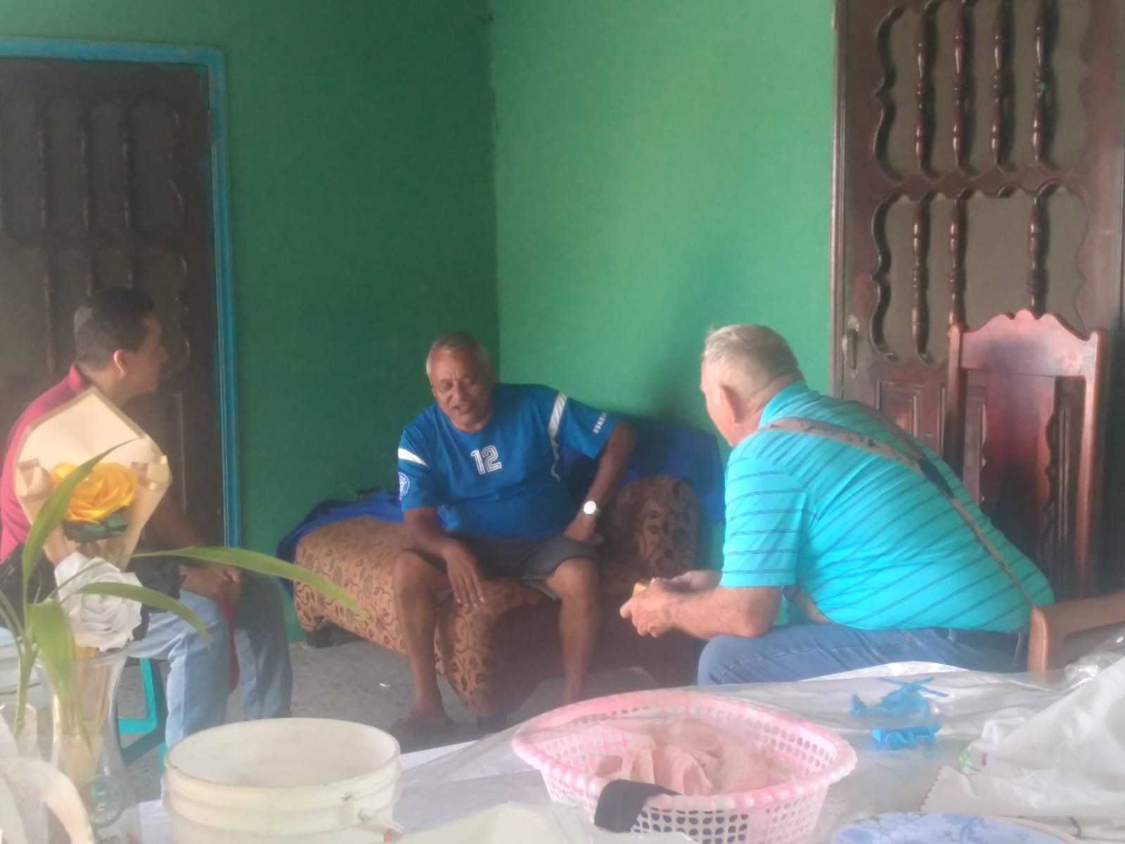 A group of men are sitting in a living room talking to each other.
