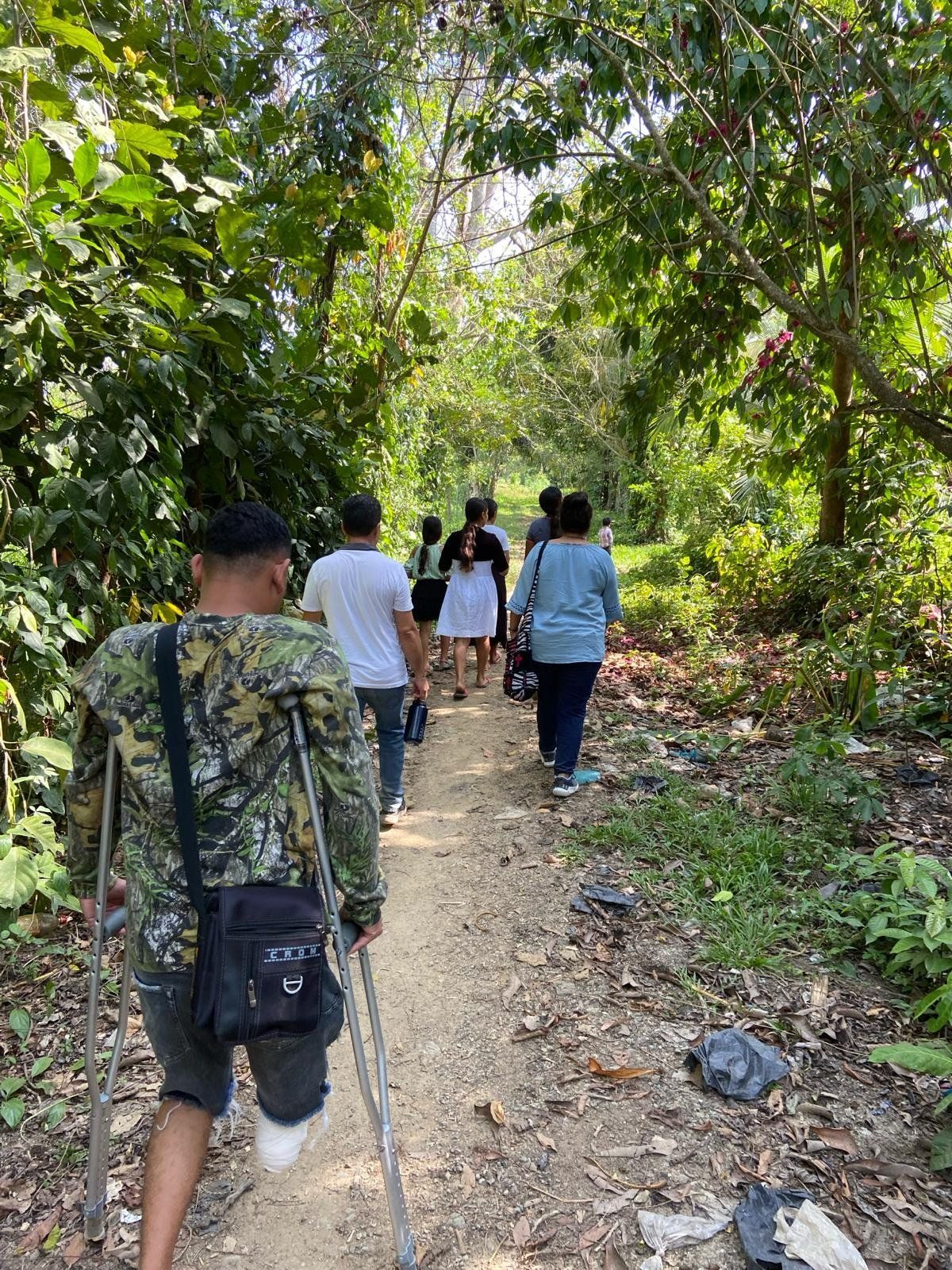 A group of people are walking down a dirt path in the woods.