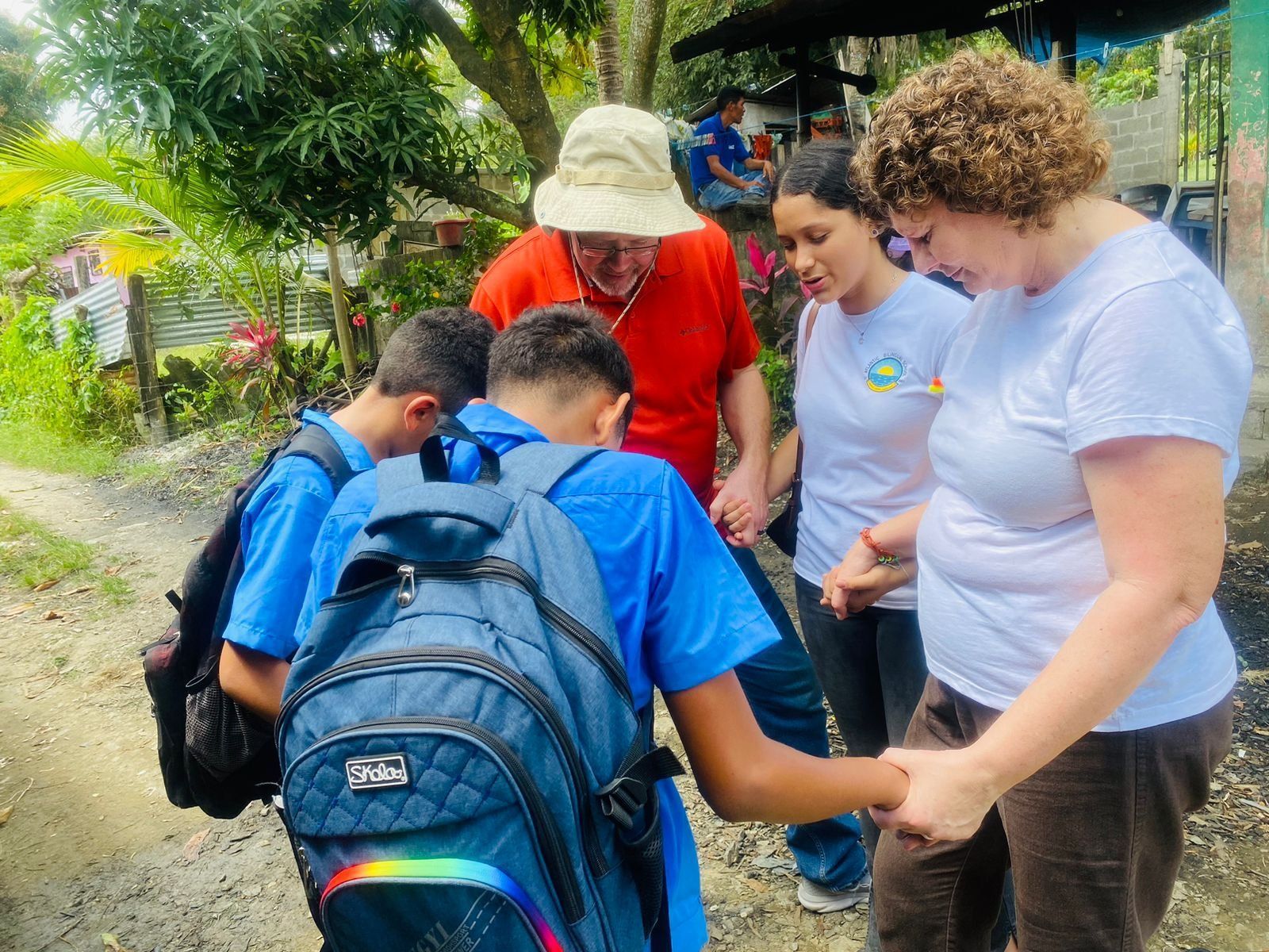 A group of people are standing around a boy with a backpack.