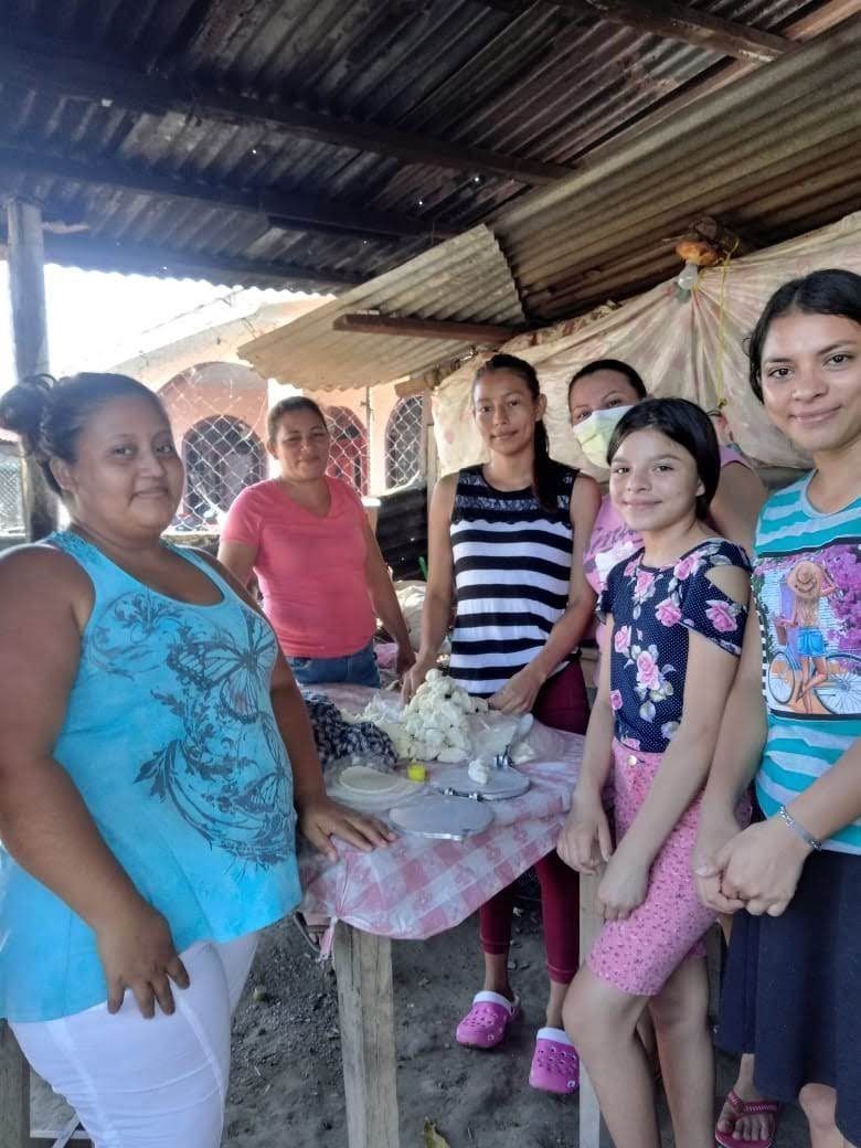 A group of women and children are standing around a table.